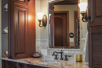 Mid-sized traditional master bathroom in Denver with raised-panel cabinets, dark wood cabinets, gray tile, white walls, an undermount sink and granite benchtops.