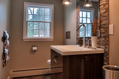 This is an example of a contemporary powder room in Boston with flat-panel cabinets, dark wood cabinets, marble benchtops, multi-coloured tile, glass tile and an integrated sink.