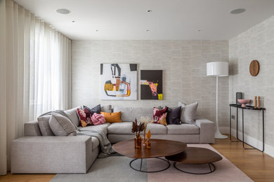 This is an example of a contemporary living room curtain in Cambridgeshire with beige walls, medium hardwood flooring and wallpapered walls.