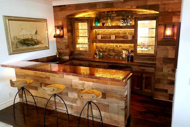 Photo of a mid-sized country u-shaped seated home bar in Orange County with a drop-in sink, shaker cabinets, distressed cabinets, copper benchtops, brown splashback, timber splashback, dark hardwood floors and brown floor.