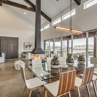 Foto på en funkis matplats med öppen planlösning, med grå väggar, betonggolv och en hängande öppen spis