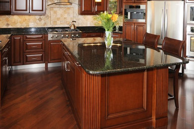 Photo of a large traditional u-shaped separate kitchen in Toronto with raised-panel cabinets, dark wood cabinets, granite benchtops, beige splashback, stone tile splashback, stainless steel appliances, dark hardwood floors and with island.