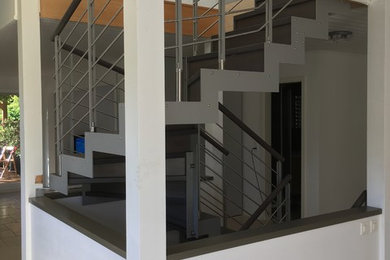 Exemple d'un grand escalier chic en U avec des marches en bois, des contremarches en bois et un garde-corps en métal.