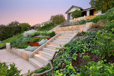 This is an example of a mediterranean front yard full sun xeriscape for fall in Sydney with a garden path and natural stone pavers.