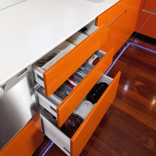 Photo of a mid-sized contemporary l-shaped kitchen pantry in Perth with an integrated sink, flat-panel cabinets, orange cabinets, solid surface benchtops, metallic splashback, glass sheet splashback, stainless steel appliances, dark hardwood floors and no island.
