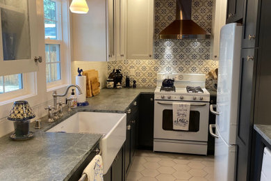 Small farmhouse galley porcelain tile, gray floor and wood ceiling kitchen photo in Other with a farmhouse sink, shaker cabinets, blue cabinets, soapstone countertops, white backsplash, subway tile backsplash and white appliances