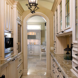 Photo of a large traditional galley kitchen pantry in Calgary with granite benchtops, beige splashback, stainless steel appliances, limestone floors, ceramic splashback and no island.