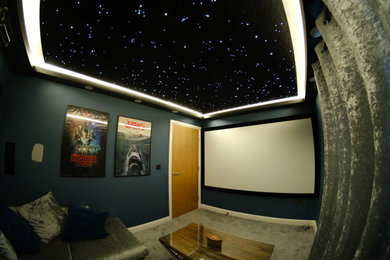 Photo of a small modern enclosed home cinema in Manchester with grey walls, carpet, a projector screen and grey floors.