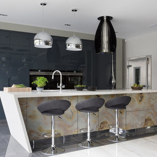 Large contemporary kitchen pantry designs - Large trendy galley porcelain floor and gray floor kitchen pantry photo in Hertfordshire with an undermount sink, flat-panel cabinets, distressed cabinets, quartzite countertops, black appliances, an island and white countertops