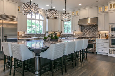 Large traditional eat-in kitchen in Nashville with flat-panel cabinets, white cabinets, granite benchtops, grey splashback, glass tile splashback, stainless steel appliances, dark hardwood floors, with island, brown floor and multi-coloured benchtop.
