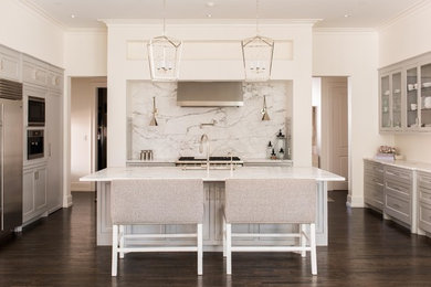 This is an example of a large transitional u-shaped kitchen in Dallas with recessed-panel cabinets, grey cabinets, marble benchtops, stainless steel appliances, dark hardwood floors, with island, an undermount sink, white splashback, stone slab splashback and brown floor.