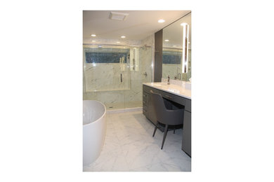 This is an example of a mid-sized contemporary master bathroom in New York with flat-panel cabinets, grey cabinets, a freestanding tub, a double shower, a two-piece toilet, black and white tile, ceramic tile, grey walls, ceramic floors, an undermount sink, engineered quartz benchtops, multi-coloured floor, a hinged shower door and white benchtops.