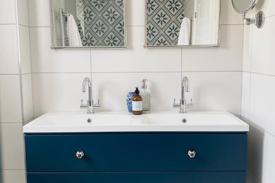This is an example of a small contemporary shower room bathroom in Cambridgeshire with flat-panel cabinets, blue cabinets, a walk-in shower, multi-coloured tiles, porcelain tiles, mosaic tile flooring, an open shower, a feature wall, double sinks and a floating vanity unit.