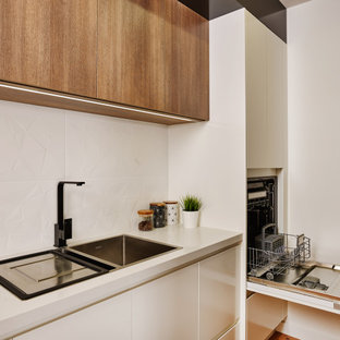 Zweizeilige, Große Moderne Küche mit Vorratsschrank, Einbauwaschbecken, flächenbündigen Schrankfronten, hellbraunen Holzschränken, Quarzwerkstein-Arbeitsplatte, Küchenrückwand in Weiß, Rückwand aus Keramikfliesen, Küchengeräten aus Edelstahl, Laminat, zwei Kücheninseln, braunem Boden und weißer Arbeitsplatte in Sonstige