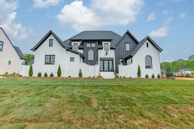 Huge transitional white two-story brick and board and batten exterior home photo in Charlotte with a shingle roof and a black roof
