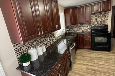 Eat-in kitchen - mid-sized traditional l-shaped ceramic tile and beige floor eat-in kitchen idea in New York with a drop-in sink, brown cabinets, marble countertops, beige backsplash, ceramic backsplash, stainless steel appliances, no island and black countertops