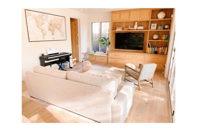 Mid-sized cottage open concept light wood floor family room library photo in San Francisco with white walls and a media wall