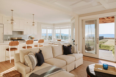 Inspiration for a large coastal open concept light wood floor, beige floor and coffered ceiling living room remodel in Portland Maine with beige walls, a standard fireplace, a stone fireplace and a wall-mounted tv