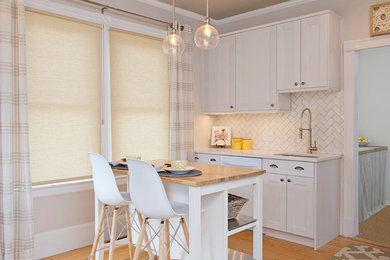 Kitchen - small transitional l-shaped light wood floor kitchen idea in Boston with shaker cabinets, white cabinets, quartz countertops, white backsplash, an island, an undermount sink, subway tile backsplash and white appliances