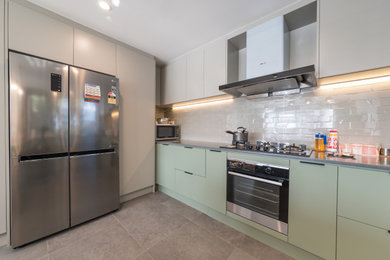 Large u-shaped open plan kitchen in Melbourne with a single-bowl sink, flat-panel cabinets, green cabinets, limestone benchtops, white splashback, subway tile splashback, stainless steel appliances, ceramic floors, beige floor and grey benchtop.