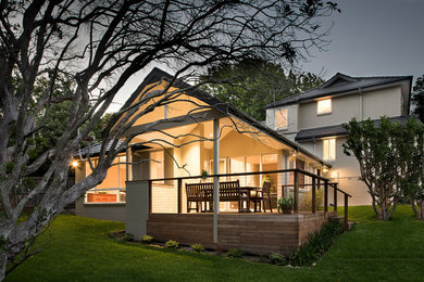 Large contemporary three-storey concrete beige house exterior in Sydney with a hip roof and a tile roof.