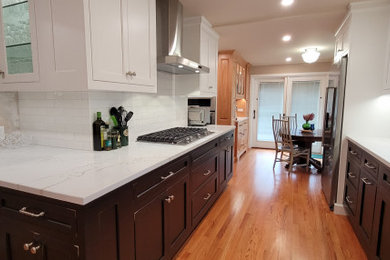 Small transitional galley light wood floor enclosed kitchen photo in Boston with an undermount sink, recessed-panel cabinets, quartz countertops, white backsplash, ceramic backsplash, stainless steel appliances and white countertops