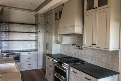 Example of a large medium tone wood floor and brown floor kitchen design in Portland with a farmhouse sink, gray backsplash, cement tile backsplash and black countertops
