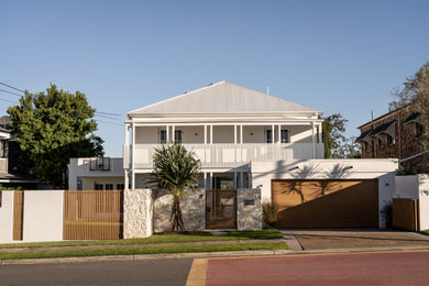 Foto della villa grande bianca a due piani con rivestimento in mattone verniciato, tetto a padiglione, copertura in metallo o lamiera e tetto bianco