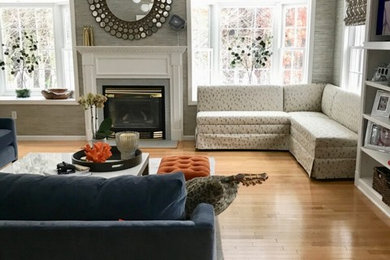 Photo of a large transitional open concept family room in Boston with grey walls, light hardwood floors, a standard fireplace, a wood fireplace surround and beige floor.
