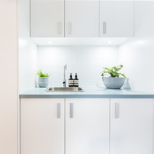 This is an example of a small traditional single-wall separated utility room in Canberra - Queanbeyan with a built-in sink, white cabinets, laminate countertops, white walls, light hardwood flooring, an integrated washer and dryer, beige floors and turquoise worktops.