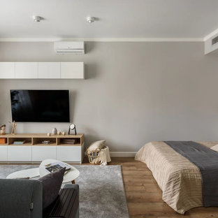 Ispirazione per un home theatre scandinavo di medie dimensioni e chiuso con pareti grigie, pavimento in laminato, TV a parete e pavimento marrone