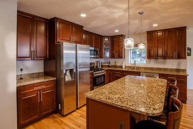 Open concept kitchen - mid-sized traditional l-shaped medium tone wood floor and brown floor open concept kitchen idea in DC Metro with stainless steel appliances, an island, an undermount sink, raised-panel cabinets, dark wood cabinets and granite countertops
