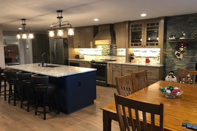 Inspiration for an expansive country galley open plan kitchen in Omaha with an undermount sink, shaker cabinets, brown cabinets, granite benchtops, beige splashback, stone tile splashback, laminate floors, with island, brown floor and beige benchtop.