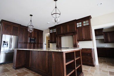Inspiration for a mid-sized timeless u-shaped limestone floor eat-in kitchen remodel in Other with a drop-in sink, flat-panel cabinets, dark wood cabinets, granite countertops, stainless steel appliances and an island