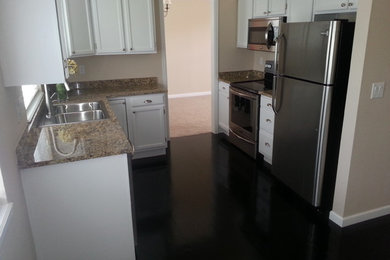 Eat-in kitchen - small transitional u-shaped laminate floor and brown floor eat-in kitchen idea in Other with a drop-in sink, shaker cabinets, white cabinets, solid surface countertops, stainless steel appliances, no island and multicolored countertops
