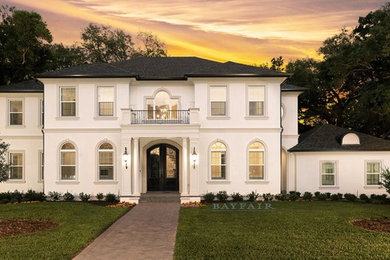 Inspiration for a large traditional two-storey stucco beige house exterior in Tampa with a hip roof and a shingle roof.