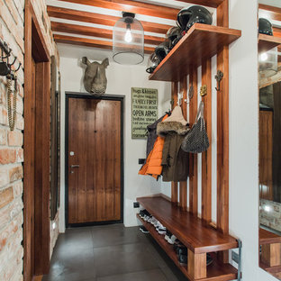 Exemple d'une porte d'entrée éclectique avec un mur blanc, une porte simple, une porte en bois brun et un sol gris.