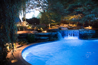 Example of a huge backyard stamped concrete and custom-shaped pool landscaping design in Other
