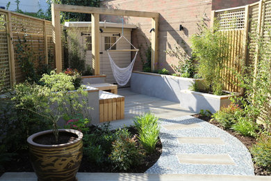This is an example of a small contemporary backyard formal garden in London with with outdoor playset and decking.