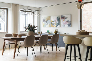 This is an example of a medium sized contemporary open plan dining room in London with white walls, light hardwood flooring, beige floors and feature lighting.