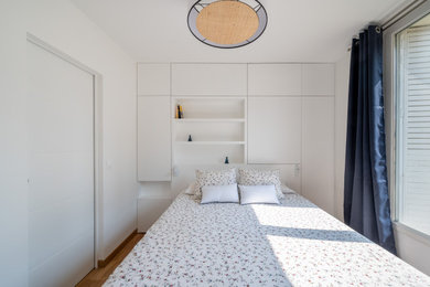 Idée de décoration pour une chambre parentale minimaliste de taille moyenne avec un mur blanc, parquet clair, aucune cheminée et un sol marron.