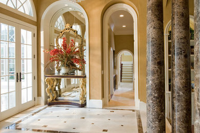 Design ideas for a large traditional foyer in Tampa with brown walls, marble floors, a double front door, a white front door and beige floor.