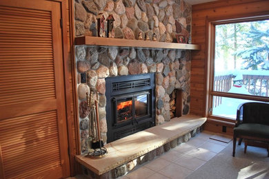 Example of a mid-sized mountain style formal and enclosed ceramic tile living room design in Other with multicolored walls, a standard fireplace, a stone fireplace and no tv