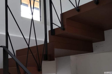 Ejemplo de escalera en L actual con escalones de metal, contrahuellas de metal y barandilla de metal