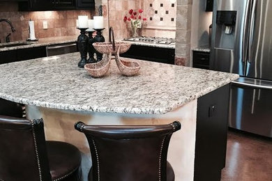 Inspiration for a mid-sized rustic l-shaped concrete floor eat-in kitchen remodel in Austin with an undermount sink, raised-panel cabinets, black cabinets, granite countertops, beige backsplash, ceramic backsplash, stainless steel appliances and an island