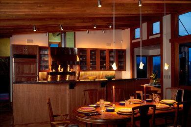 Single-wall concrete floor eat-in kitchen photo in Denver with glass-front cabinets, medium tone wood cabinets, granite countertops and an island
