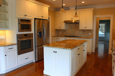 Eat-in kitchen - mid-sized traditional l-shaped medium tone wood floor and brown floor eat-in kitchen idea in New York with an undermount sink, raised-panel cabinets, white cabinets, granite countertops, beige backsplash, porcelain backsplash, stainless steel appliances and an island