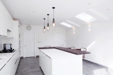 Contemporary kitchen/diner in Other with flat-panel cabinets, white cabinets, an island, grey floors, wood worktops, white splashback and porcelain flooring.