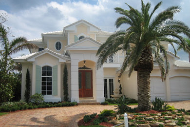 Design ideas for a large tropical two-storey stucco beige exterior in Miami.