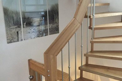 Ejemplo de escalera curva contemporánea con escalones de madera y barandilla de varios materiales